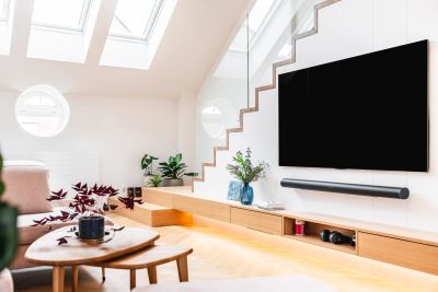 Obývací pokoj — schodiště s TV stěnou, růžová sedačka a kulaté okénko pod střešními okny