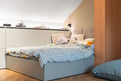 Dětský pokoj — postel s kostkovaným povlečením u dřevěného sloupu