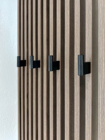 Detail kovových věšáčků na lamelové stěně