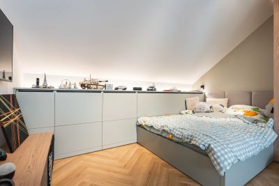 Dětský pokoj — postel se šedomodrým kostkovaným povlečením u vestavěné skříně