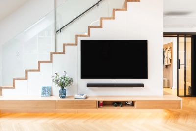 Obývací pokoj — schodiště se skleněným zábradlím a TV stěna s odkládací skříňkou